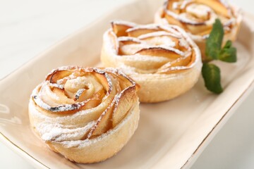 Freshly baked apple roses with mint on white table, closeup