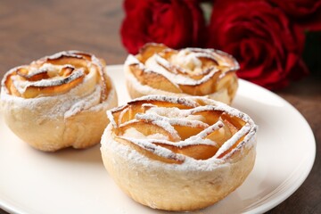 Freshly baked apple roses and beautiful flowers on table, closeup