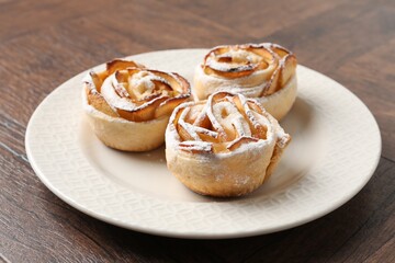 Freshly baked apple roses on wooden table, closeup