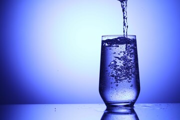 Pouring refreshing soda water into glass on blue background, closeup. Space for text