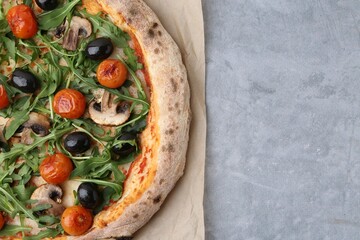 Tasty pizza with cherry tomatoes, black olives, mushrooms and arugula on grey table, top view. Space for text