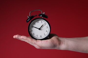 Man with alarm clock on red background, closeup