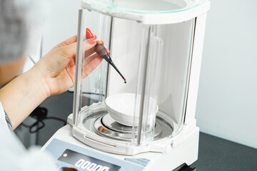 Precision weighing of liquid in a laboratory setup with an analytical balance during a research...