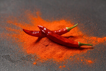 Red chili powder and peppers on black background