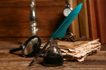 Old book with nib pen, inkwell and magnifying glass on wooden background