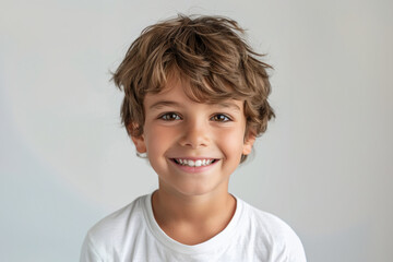 A young boy, dressed casually, smiles brightly against a neutral background, his relaxed pose and vibrant personality embodying innocence and happiness.