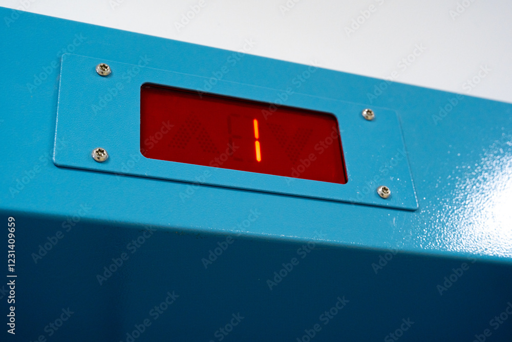 Poster digital display shows a countdown of one on a bright blue panel mounted on a wall in a contemporary 