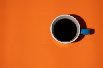 Top view of blue mug on a minimalist orange background with copy space