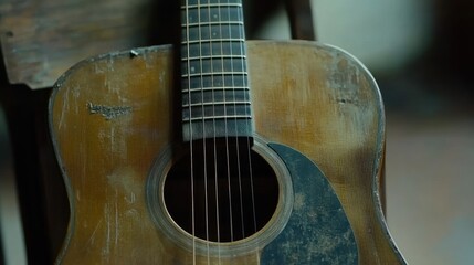 Fototapeta premium Close-up of a weathered acoustic guitar, showing its worn body, fretboard, and soundhole.