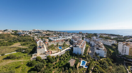 Obraz premium Aerial drone photo of the beautiful town of Sitio de Calahonda taken in the winter time showing residential and holiday homes with swimming pools from above and the ocean front in the background