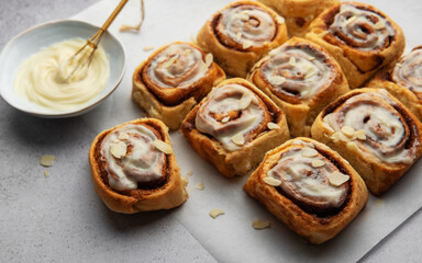 Freshly baked cinnamon rolls topped with cream cheese frosting and almond slivers