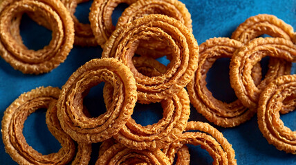 Crispy golden chakli snacks beautifully coiled on blue background, perfect for sharing and enjoying