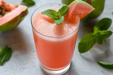 A glass of refreshing guava juice with a light pink color, served with a guava slice and a few fresh mint leaves