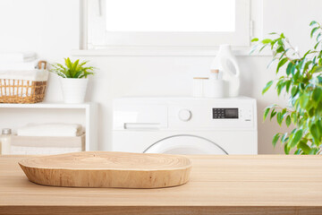 Wooden round podium pedestal for product presentation on blurred background of laundry room