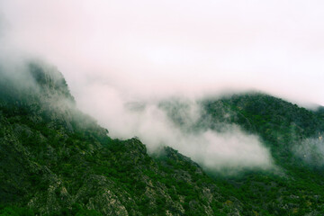 Fog covering mountain slopes near calm water