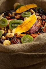 Dried tropical fruits and nuts in burlap bag.