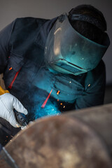 Industrial worker welding metal with sparks flying