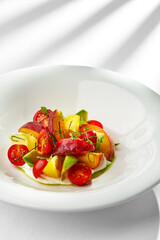 A vibrant and refreshing summer salad featuring ripe tomatoes, creamy avocado, and sweet peaches. The salad is tossed in a light vinaigrette and served on a bed of fresh greens.