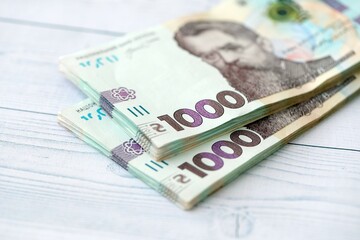 Big amount of ukrainian new one hundred hryvnia money bills with modern design on white wooden table. Financial concept, business