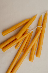Handmade beeswax candles lie on a light fabric background