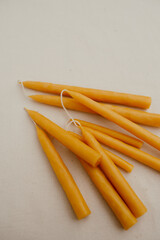 Handmade beeswax candles lie on a light fabric background