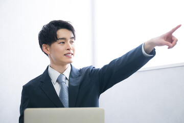 目標や未来を目指して指を差す若い20代のスーツをの男性
