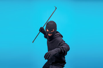 Portrait Of Burglar In Action With Crowbar Isolated On Blue Background 