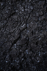 Abstract dark grey stone texture. Close up of limestone rock wall. Surface with cracks. Modern gray grunge background with space for design. Granite. Slab. Nature Background. Vertical.