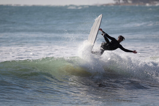 Surfer performing trick on ocean wave during sunny day
