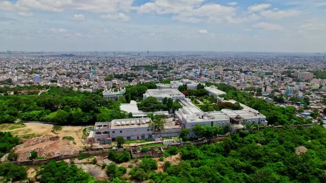 Taj groups luxury hotel falaknuma palace in hyderabad with trees and cityscape at engine bowli, falaknuma, hyderabad, telangana, india. day time, drone shot, 4k.