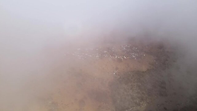 Dense mist covering Cedros Island&rsquo;s coastline, dramatic and moody weather scene in the early morning, aerial flythrough reveals town in hillside