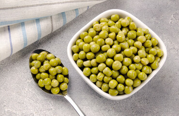 Canned green peas in a plate on a gray background