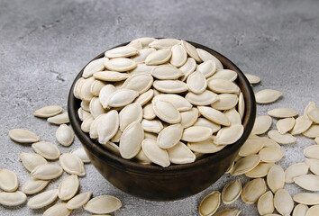 A bowl of pumpkin seeds on a gray background