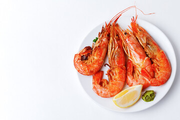 Grilled shrimps on plate with lemon and pesto sauce isolated on a white background.