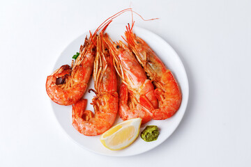 Grilled Langoustines on plate with lemon and pesto sauce isolated on a white background.
