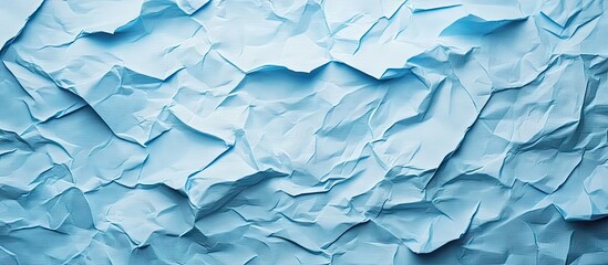 Obraz premium Crinkled light blue paper texture background showcasing various shades of blue and creases, perfect for creative design projects and wallpapers