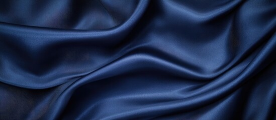 Fototapeta premium Elegant navy blue satin fabric folds creating a rich texture with soft highlights and shadows ideal for sophisticated design backgrounds.