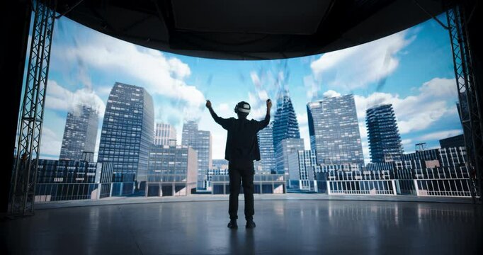 Architectural Designer in a VR Headset Designs Futuristic Cityscapes on a Big Panoramic Digital Screen that Reflects His Computer Vision. Virtual Reality Technology Innovation and Creativity Concept