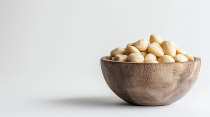 rustic wooden bowl filled with macadamia nuts, showcasing minimalist aesthetic. smooth texture and natural color of nuts create calming visual appeal