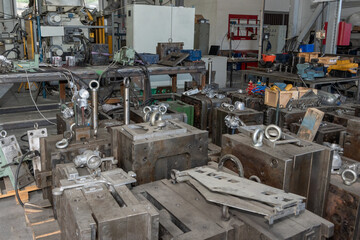 Workshop with industrial equipment and metal components on tables.
