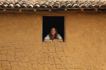 mulher me janela de casa de pau a pique