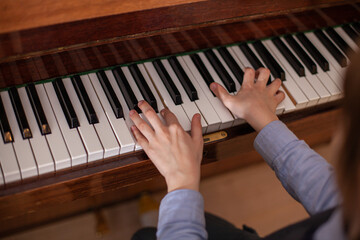 Close up of boy's hands playing piano. Child has piano lesson. Development of musical abilities. Top view. Selective focus.
