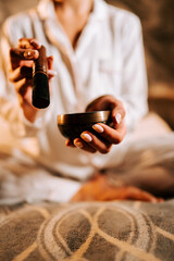 Woman meditating with Tibetan singing bowl during a serene moment in a cozy indoor space