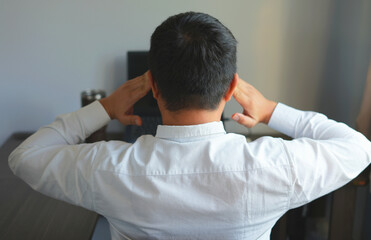 An asian male officer getting pain on his sore back, shoulder and head and massaging himself to get...
