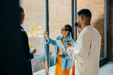 Informal business meeting with diverse team brainstorming with sticky notes in a modern office...