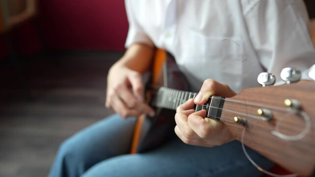 Girl playing acoustic balalaika swiftly with plucking motion at home. Create home music, classic and ethnic musical instruments, practicing memorizing frets and strum. High angle view