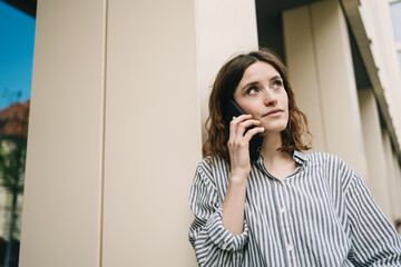 Woman standing by building talking on phone
