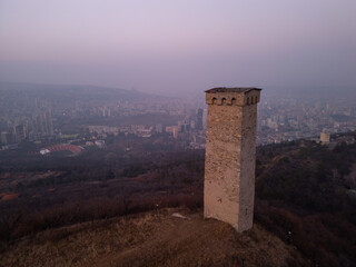 Ancient tower opposite city skyscrapers in Georgia - aerial view
