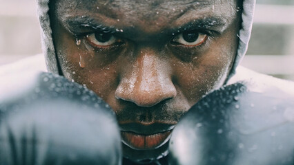 Intense boxer focused in ring, sweat glistening on his face, ready to fight