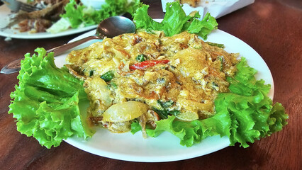 A delectable Thai Crispy Soft Shell Crab in Curry Sauce, rich with savory flavors and vibrant colors, served on a bed of fresh lettuce. The dish is presented beautifully, enticing the appetite.